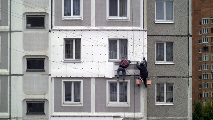 Naklejka premium climbers work on the building, climbers are working on the insulation of facades of a multi-storey residential building