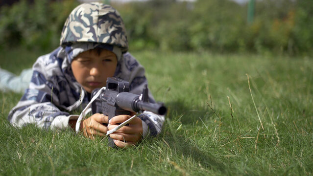 boy in camoflauge playing war shoots a toy gun, have fun and enjoy