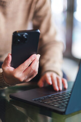 Vertical closeup image of a woman using smart phone and laptop computer