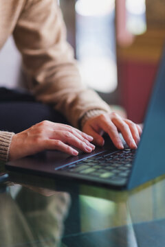 Vertical closeup image of a woman hand working and typing on laptop computer