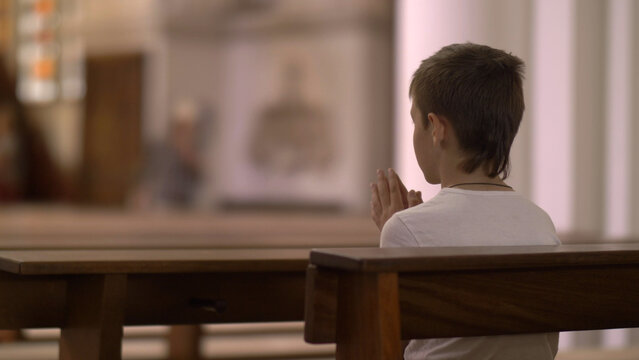 serious boy praying in the Church alone, have fun and enjoy