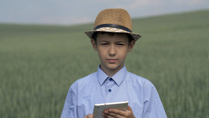 boy farmer with a tablet stands in the field and looks into the camera, have fun and enjoy © vla