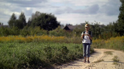 Obraz premium happy boy traveler in a hat walking and using a tablet, outdoors, have fun and enjoy