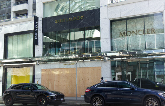 Boarded up Prada and Moncler luxury retail stores with plywood w