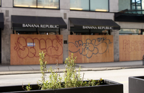 Banana Republic store boarded up with plywood covered in graffit