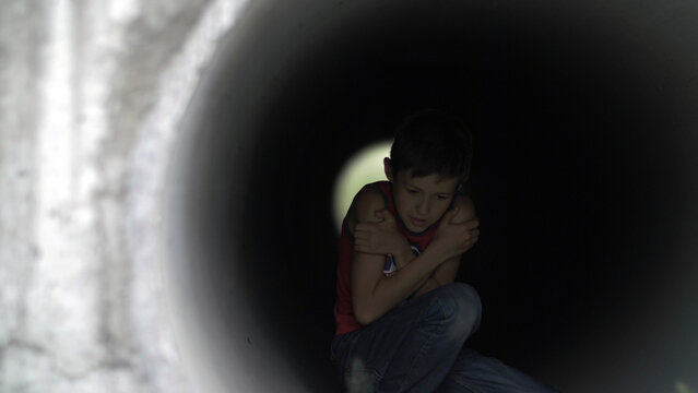 homeless lonely boy hiding inside of a drainage tunnel from the frost trying to keep warm, have fun and enjoy