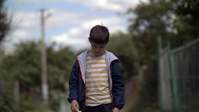 lonely sad boy walking along the village road with head down, ruffian naughty boy, have fun and enjoy