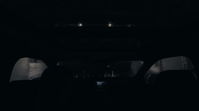 POV wide shot of Driver inside vehicle entering automatic car wash with visible interior view and glass roof.