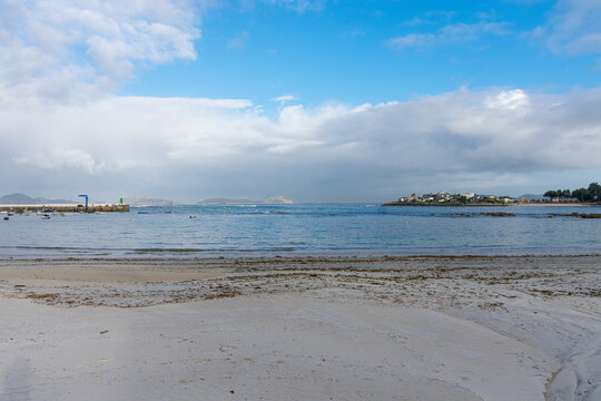 Coastal landscape of the Vigo estuary with the Canido pier and the Cies Islands under a bright blue sky today