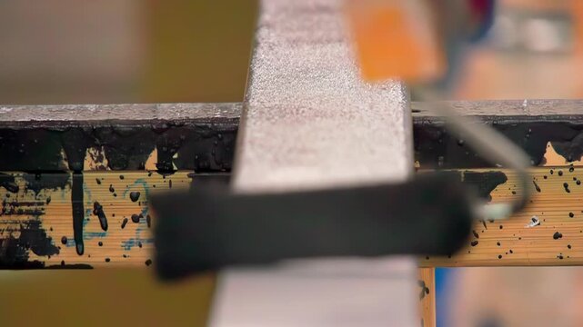 Paint roller applies black coating on metal frame in industrial setup