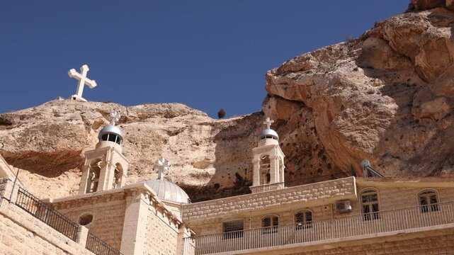 Cinematic exterior shot of the historic Saint Thecla Monastery built into the dramatic mountain cliffs of Ma'aloula