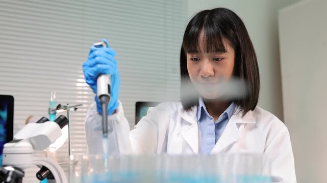 Female scientist using a micropipette in a modern laboratory.