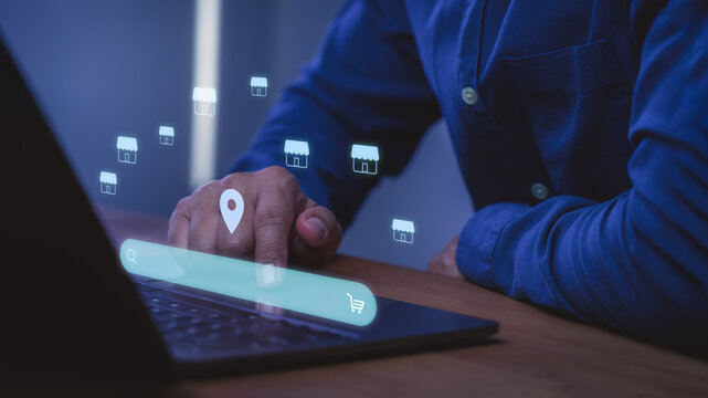 Man using laptop with virtual search bar, location pin, and store icons. Concept of ecommerce, online shopping, franchise business, retail expansion, and digital marketing technology.