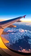 Fototapeta premium View from an airplane window, showing wing, clouds, and sky at sunset