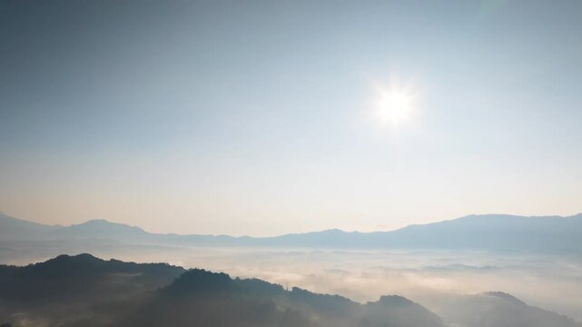 Hyperlapse by dorne Spectacular aerial view of a sea of mist covering mountain ranges under a bright mornig sun. Captures peaceful nature, morning fog, and scenic horizons at sunrise.