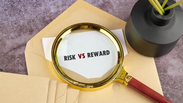 A magnifying glass slowly reveals the words Risk versus Reward written on a white paper. The paper sits on a brown envelope on a grey desk surface