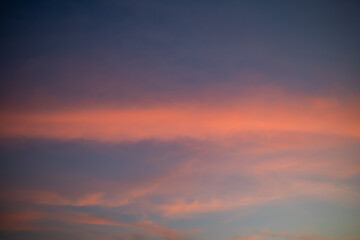 Obraz premium Pink clouds glowing at sunset, soft pastel sky with warm golden light blending into blue tones, calm and dreamy atmosphere, natural sky background