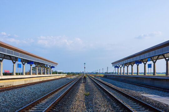Perspective view of rural train station in beautiful countryside with railway tracks.