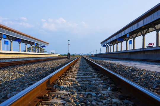 Perspective view of rural train station in beautiful countryside with railway tracks.