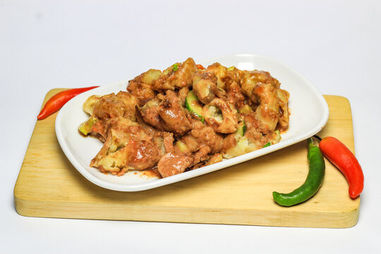 Indonesian batagor with rich peanut sauce and chili peppers on wooden board, isolated on white for spicy street food concept