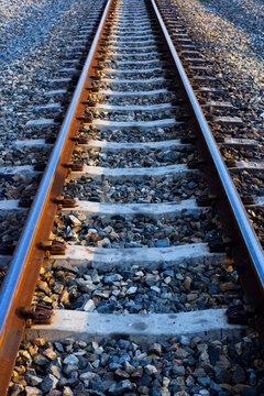 Perspective view of railway tracks stretching forward with ballast crushed stones.