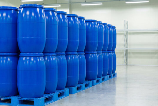 Stacks of bright blue industrial plastic barrels on pallets