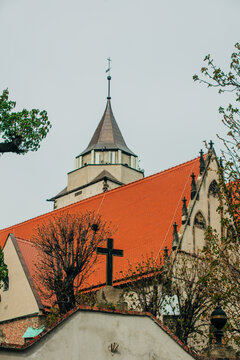 Catholic Christian cross at church courtyard entrance with 18th century facade background, Europe