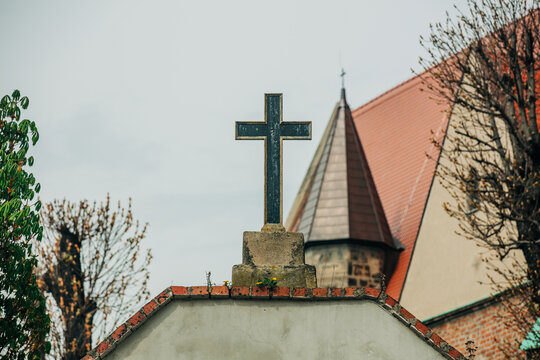 Catholic Christian cross at church courtyard entrance with 18th century facade background, Europe