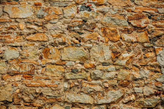 Rough 16th century stone wall, yellow stone blocks, textured facade background, Europe