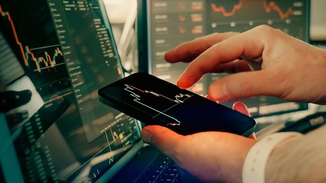 Professional day trader monitoring volatile financial markets on multiple screens and smartphone during intense global stock exchange sessions for corporate advertising.