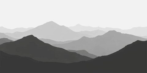 A misty mountain landscape at sunrise reveals a vast range of peaks and valleys under a blue morning sky where clouds and fog drift over the silhouetted hills and horizon © BIBI