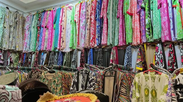 Colorful traditional dresses on display in a shop window at a textile market in Uzbekistan