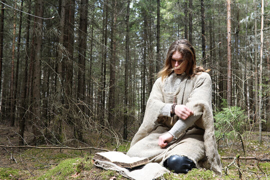 A man in a cassock spends a ritual in a dark forest