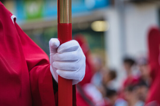 Nazarene with a white glove holds a processional candle