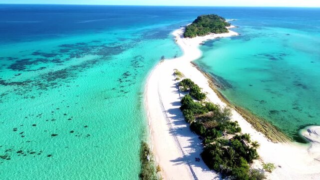 Cinematic aerial drone footage of a remote island paradise with a white sand beach and clear blue ocean.