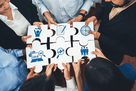 Diverse corporate officer workers collaborate in office, connecting puzzle pieces to represent partnership and teamwork. Unity and synergy in business concept by merging jigsaw puzzle. Concord Amity