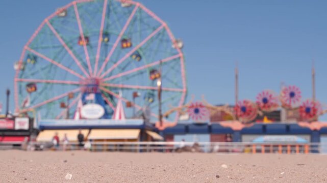 Coney Island sandy beach in Brooklyn, New York, United States. Boardwalk near retro luna park. Ferris wheel in american amusement park on ocean coast. Waterfront summer holiday promenade in NYC, USA.