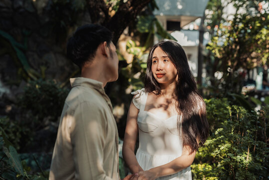 A emotional young Asian couple reconciling as the woman feels deeply moved by her boyfriend&rsquo;s sincere words and heartfelt apology. Outdoor shot.