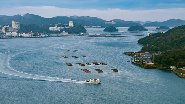 日本：三ツ島をバックにホタテの養殖所と波を立てる船【伊勢志摩国立公園】三重県鳥羽市