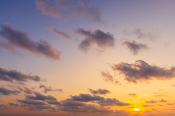 Fototapeta premium Golden Sunset over the Horizon with Soft Pastel Clouds,A breathtaking sunset scene featuring a vibrant golden sun dipping toward the horizon, illuminating scattered soft clouds with warm orange.