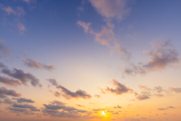 Fototapeta premium Golden Sunset over the Horizon with Soft Pastel Clouds,A breathtaking sunset scene featuring a vibrant golden sun dipping toward the horizon, illuminating scattered soft clouds with warm orange.