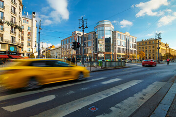 Fast moving yellow taxi on the road in Budapest with architectural buildings background.