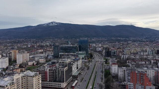 Sofia, Bulgaria - aerial forward approach toward Bulgaria Mall, glass office towers, busy boulevard and Vitosha Mountain in the background.