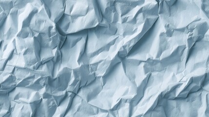 Fototapeta premium Close-up of a crumbled, wrinkled, crumpled paper texture in a soft cool-toned light blue with intricate folds and shadow