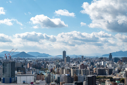 Panoramic View of Hiroshima Cityscape with Skyscrapers and Seto Inland Sea under a Blue Sky
