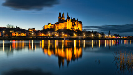 Fototapeta premium Illuminated Albrechtsburg Castle and Meissen Cathedral reflecting in Elbe river at night, Saxony, Germany - real photography - authentic - no ai