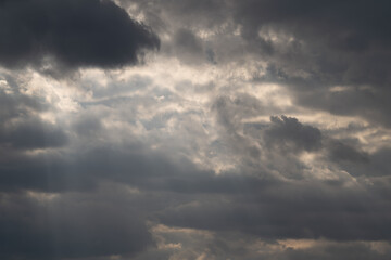 Obraz premium Cinematic clouds with light beams piercing sky, sweeping rays creating crepuscular effect, soft highlights on cloud edges, inspirational mood for film and landscape projects