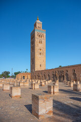 Fototapeta premium The Kutubiyya Mosque stands tall in Marrakesh, Morocco. People gather around as they admire the structure and the surrounding area during sunny weather.