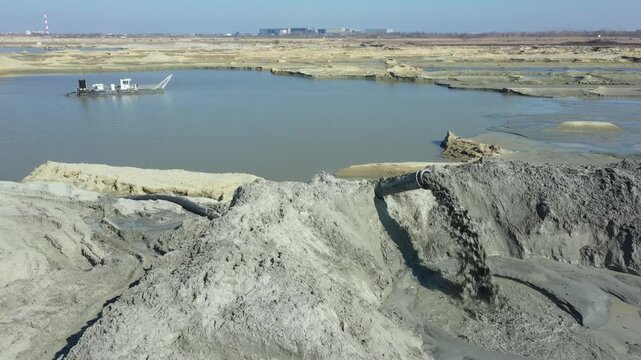 Mixture water and sand flow from big pipe, pump discharge for sand sedimentation. Water flows and carries sand from opencast surface mining, excavating sand and his deposition.