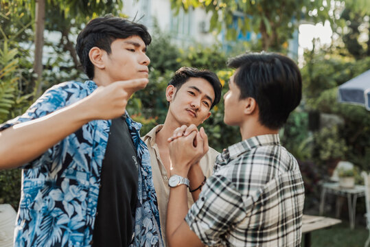 A tense young Asian men aggressively confronting a friend and demanding repayment of debt during a heated and intimidating outdoor encounter. Outdoor shot.